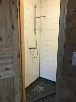 a shower in a bathroom with a tiled wall at Eidfjord Gjestgiveri in Eidfjord
