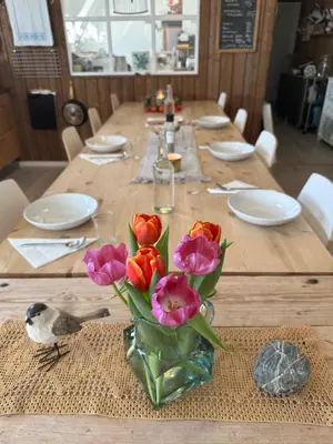 a wooden table with a vase of flowers on it at SAGA, unikt badehotell med 5 rom, sauna og badebrygge - Inderøy in Straumen