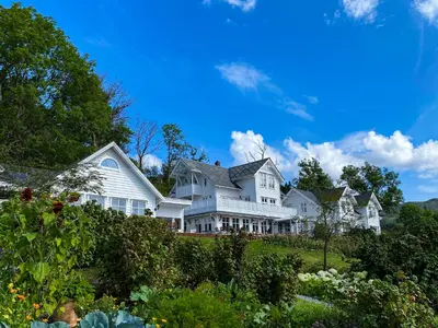 a large white house on a hill with bushes at Haaheim Gaard in Uggdal