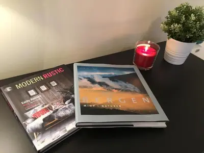 a table with a magazine and a candle and a plant at Kvamseter Lodge - Mountain Apartments in Norheimsund