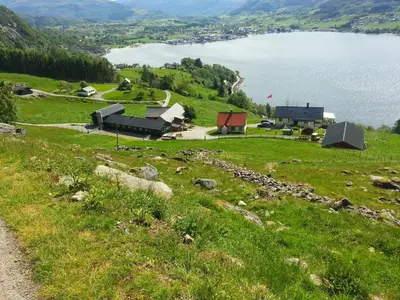 a grassy hill with a view of a lake at Etne Hytter in Etnesjøen