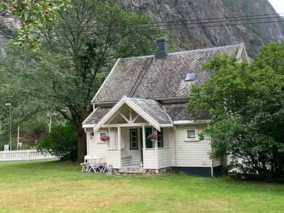 a white house with a table and chairs in a yard at Aobrio Holidayhouse, authentic norwegian farmhouse close to Flåm in Lærdalsøyri