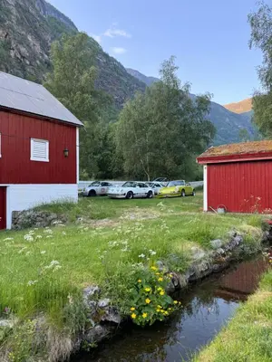 a group of cars parked next to two buildings and a creek at Aobrio Holidayhouse, authentic norwegian farmhouse close to Flåm in Lærdalsøyri