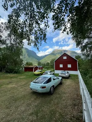 three cars parked in a field next to a red barn at Aobrio Holidayhouse, authentic norwegian farmhouse close to Flåm in Lærdalsøyri