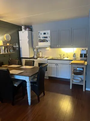 a kitchen with white cabinets and a wooden table with chairs at Storehorn Apartments Hemsedal in Hemsedal