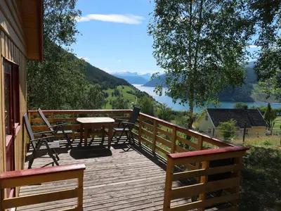a wooden deck with a table and chairs on it at Holiday Home Turken by Interhome in Kaupanger