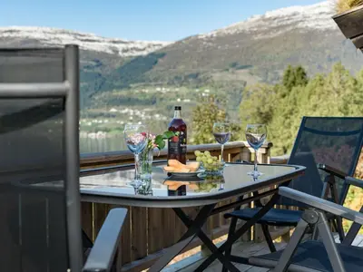 a table on a balcony with wine bottles and glasses at Chalet Fjordblick I by Interhome in Olden