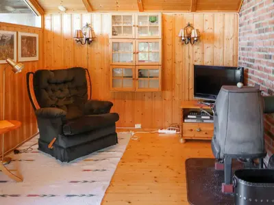 a living room with a chair and a television at Holiday Home Sandvikfjellet by Interhome in Nyttingsnes