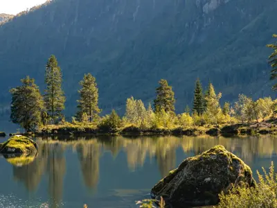 a lake in the mountains with trees and rocks at Holiday Home Strandbu by Interhome in Viksdalen
