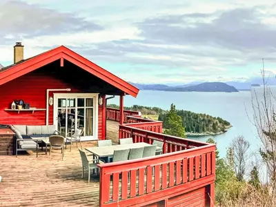 a red house with a deck with a table and chairs at Holiday Home Elistova by Interhome in Onarheim