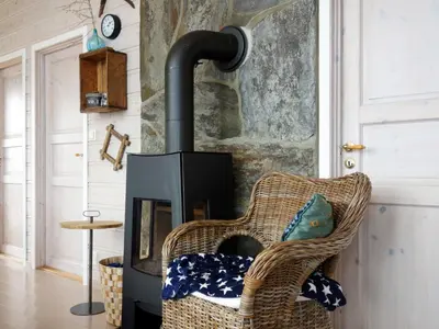 a fireplace in a living room with a wicker chair at Holiday Home Elistova by Interhome in Onarheim