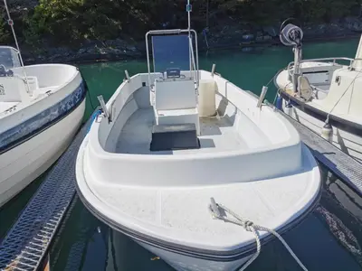 a small white boat is docked at a dock at Holiday Home Blåbærhytta by Interhome in Onarheim