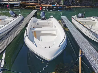 a white boat is docked at a dock at Holiday Home Tyttebærhytta by Interhome in Onarheim