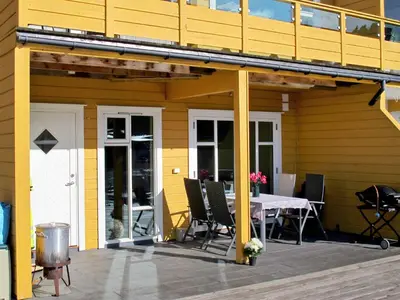 a yellow house with a table and chairs on a deck at Apartment Rorbuen by Interhome in Uggdal