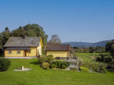 a yellow house in a field with a garden at Chalet Gulehuset by Interhome in Gjelland