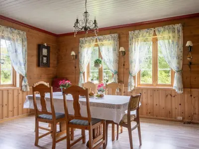 a dining room with a table and chairs and windows at Chalet Gulehuset by Interhome in Gjelland