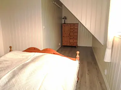 a bedroom with a bed and a dresser and stairs at Holiday Home Gamlahuset by Interhome in Bruntveit