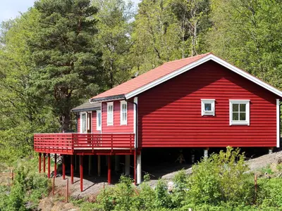 a red house with a deck in the woods at Holiday Home Rød Hytte by Interhome in Herand