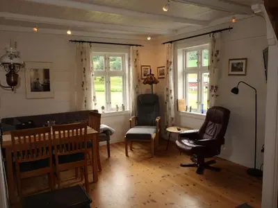 a living room with chairs and a table and windows at Holiday Home Ikjefjord by Interhome in Bjordal