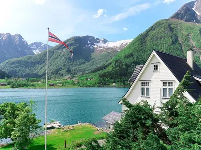 a house with a flag flying in front of a lake at Chalet Villa Esefjord by Interhome in Balestrand