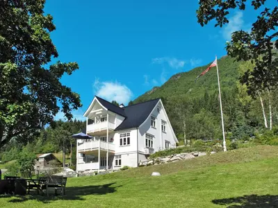 a large white house on a hill with a flag at Chalet Villa Esefjord by Interhome in Balestrand