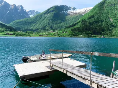 a woman sitting on a boat at a dock on a lake at Chalet Villa Esefjord by Interhome in Balestrand