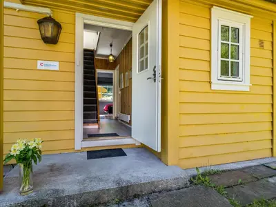 a yellow house with a white door and a vase of flowers at Holiday Home Eseviki by Interhome in Balestrand