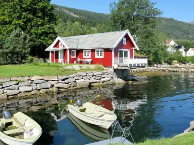 a red house with two boats in the water at Chalet Naustet by Interhome in Balestrand