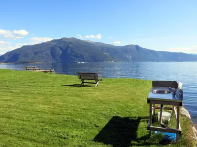 a grill sitting on the grass next to a lake at Chalet Naustet by Interhome in Balestrand