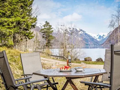 a table with a bowl of fruit and a bottle of wine at Holiday Home Veganeset I by Interhome in Balestrand