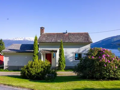 a white house with flowers in front of a lake at Holiday Home Tantestova by Interhome in Balestrand