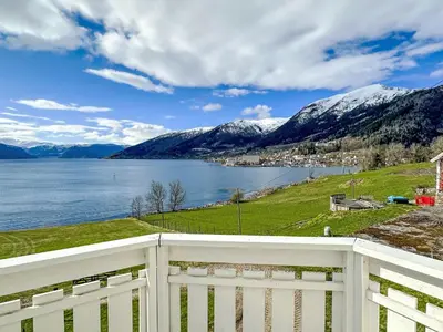a view of a lake and mountains with a white fence at Holiday Home Tantestova by Interhome in Balestrand