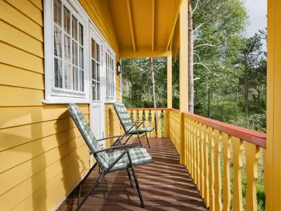 two chairs sitting on the porch of a yellow house at Holiday Home Granlien by Interhome in Gjølanger