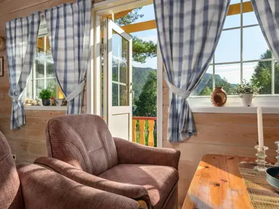 a room with a chair and a table and windows at Holiday Home Synnøve by Interhome in Gjølanger