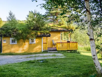 a yellow cabin with a deck and a chair on the porch at Holiday Home Synnøve by Interhome in Gjølanger