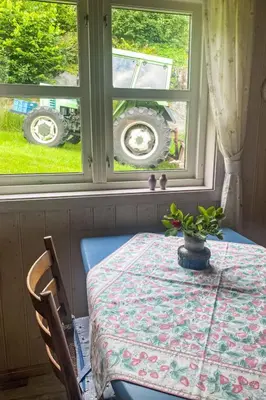 a table and two windows with a table and a tractor outside at Holiday Home Nausthammar by Interhome in Davik