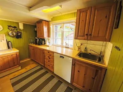 a kitchen with wooden cabinets and a sink and a window at Holiday Home Lenebu by Interhome in Syvde