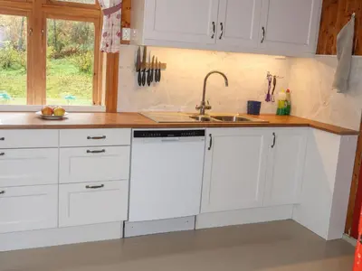 a kitchen with white cabinets and a sink at Holiday Home Elvehuset by Interhome in Holsen