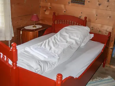a red bed in a room with a wooden wall at Holiday Home Elvehuset by Interhome in Holsen