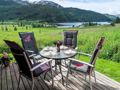a table and chairs on a deck with a view of a field at Chalet Haukedalspanorama by Interhome in Holsen