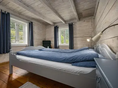 a bedroom with a large bed with blue sheets at Holiday Home Johans Maria stova by Interhome in Arnefjord