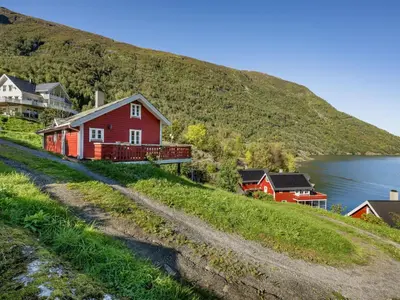 a red house on a hill next to a body of water at Holiday Home Johans Maria stova by Interhome in Arnefjord