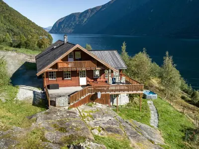a large wooden house on a hill with a lake at Holiday Home Odin by Interhome in Arnefjord