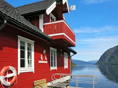 a red house on a body of water at Apartment Fagerdalsnipi by Interhome in Arnefjord
