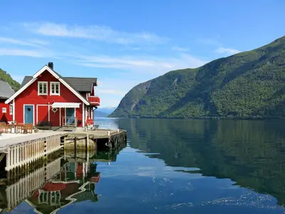 a red house on a dock on a body of water at Apartment Fagerdalsnipi by Interhome in Arnefjord