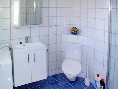 a white tiled bathroom with a toilet and a sink at Apartment Fagerdalsnipi by Interhome in Arnefjord