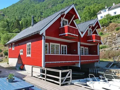 a red house on the water with boats in it at Holiday Home Jambueggi by Interhome in Arnefjord