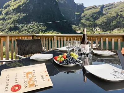 a table with a bottle of wine and a bowl of fruit at Holiday Home Indresfjord by Interhome in Åse