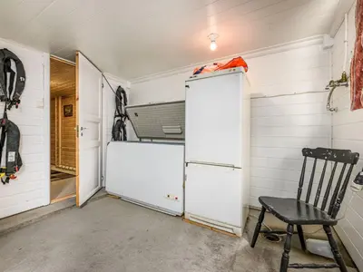 a garage with a white refrigerator and a chair at Holiday Home Indresfjord by Interhome in Åse