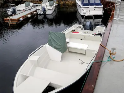 a white boat tied to a dock in the water at Holiday Home Solsvika by Interhome in Leirvik